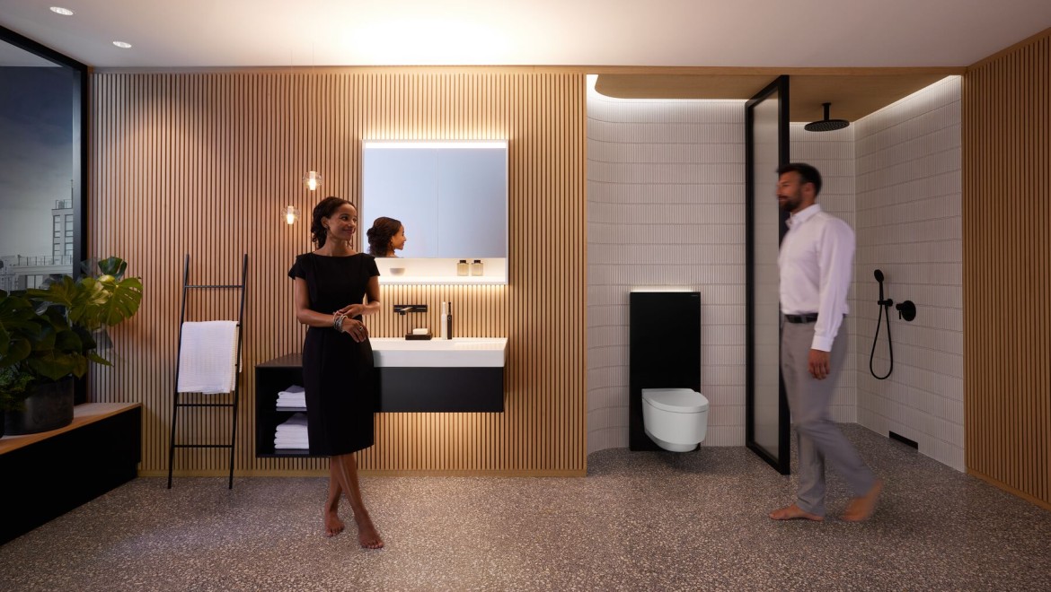 Hombre y mujer en un baño perfectamente iluminado con productos Geberit ONE