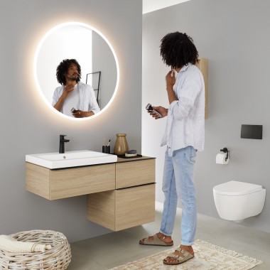 Hombre mirándose en un espejo redondo con luz Geberit Option
