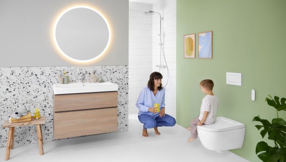 Mujer y niño en un colorido baño con espejo Geberit Option y Geberit AquaClean Alba