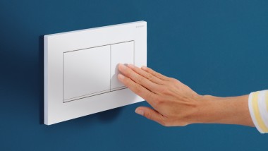 Una persona presiona el botón de la media descarga en un pulsador Sigma30 blanco
