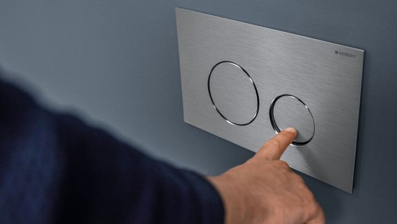 Mano presionando la media descarga en el pulsador Sigma40 Round (© Geberit) Mano presionando la media descarga en el pulsador Sigma40 Round (© Geberit)